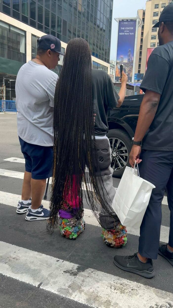 NYC locals showcasing experimental fashion with colorful, textured footwear and long braids on a city street.