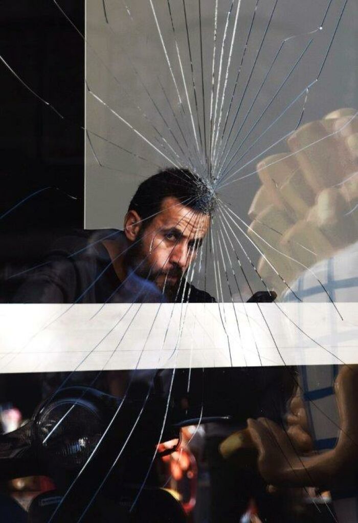 A man behind c*****d glass, captured in an everyday moment through Nadia Eeckhout's lens.