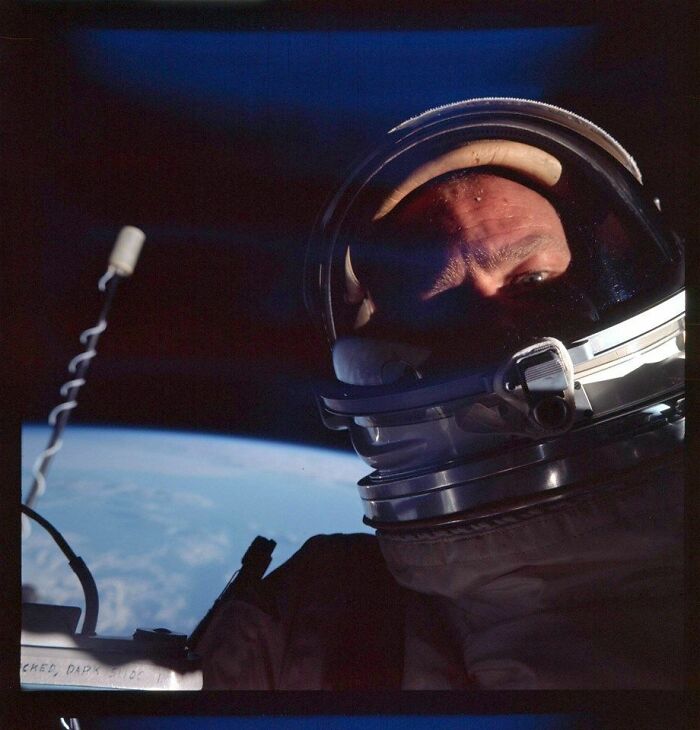 Astronaut in a spacesuit taking a selfie in space with Earth in the background, highlighting historical exploration moments.