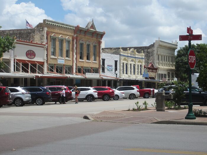 Historic buildings and parked cars on a sunny street, capturing a sense of weird unsolved mysteries in a small town.