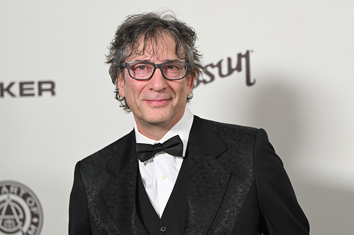 Neil Gaiman in a formal suit poses at an event.