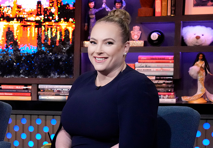 Meghan McCain smiling in a studio, surrounded by books and decor.