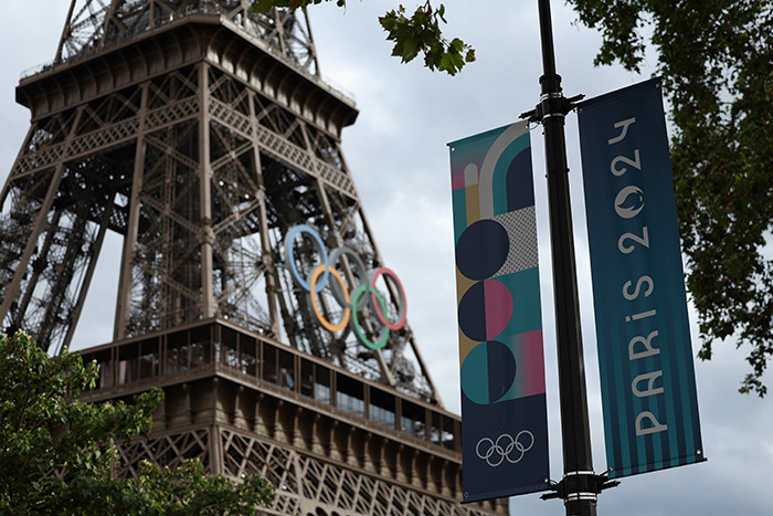 Paris 2024 Olympic sign near Eiffel Tower.
