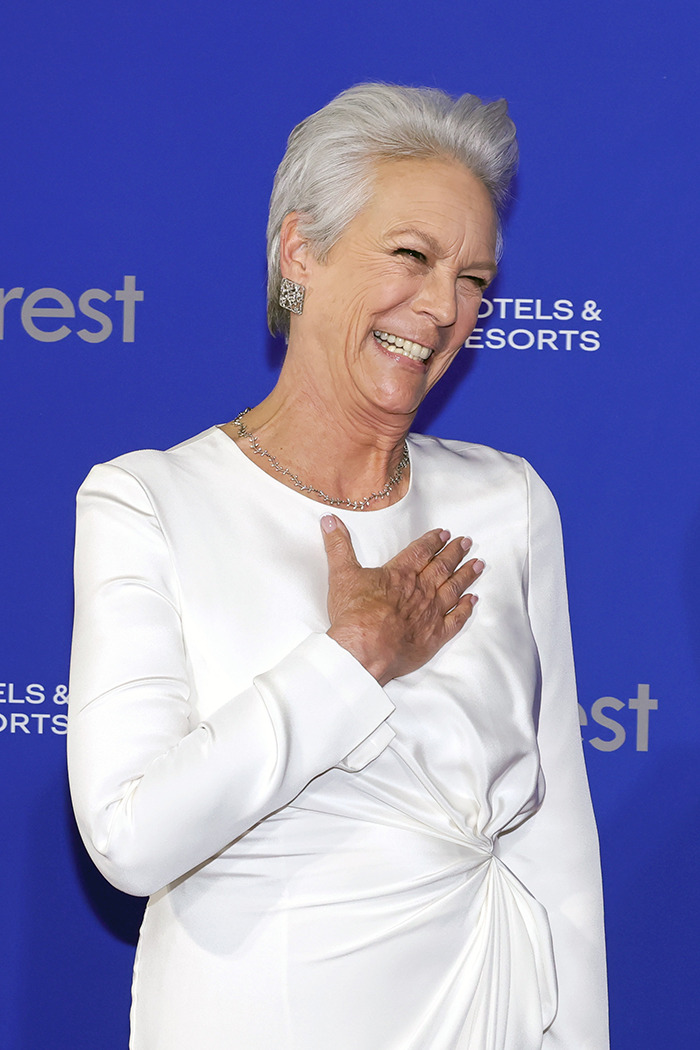 Jamie Lee Curtis in a white dress smiling.