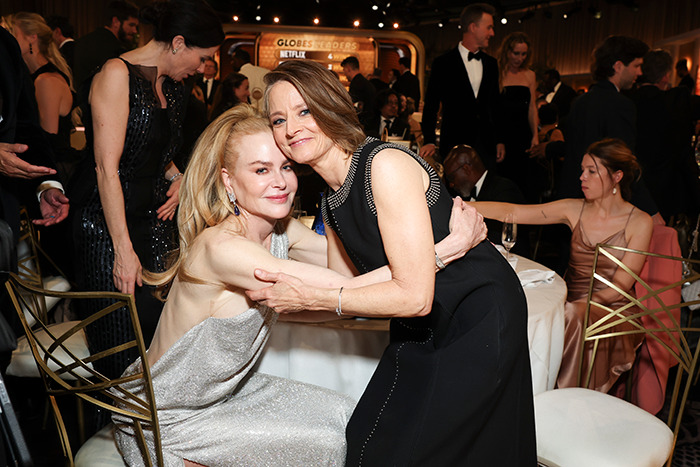 Nicole Kidman and Jodie Foster hugging at an event, surrounded by elegantly dressed attendees.