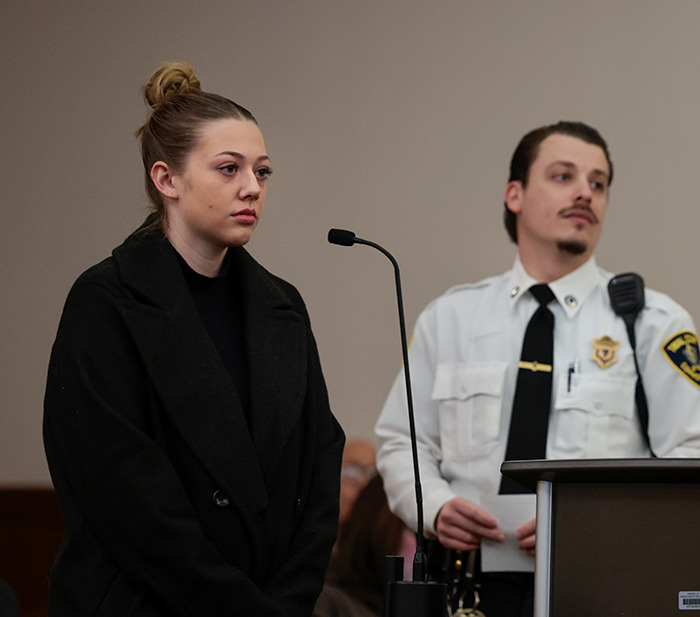 College student in courtroom with an officer, relating to a TikTok-inspired incident.