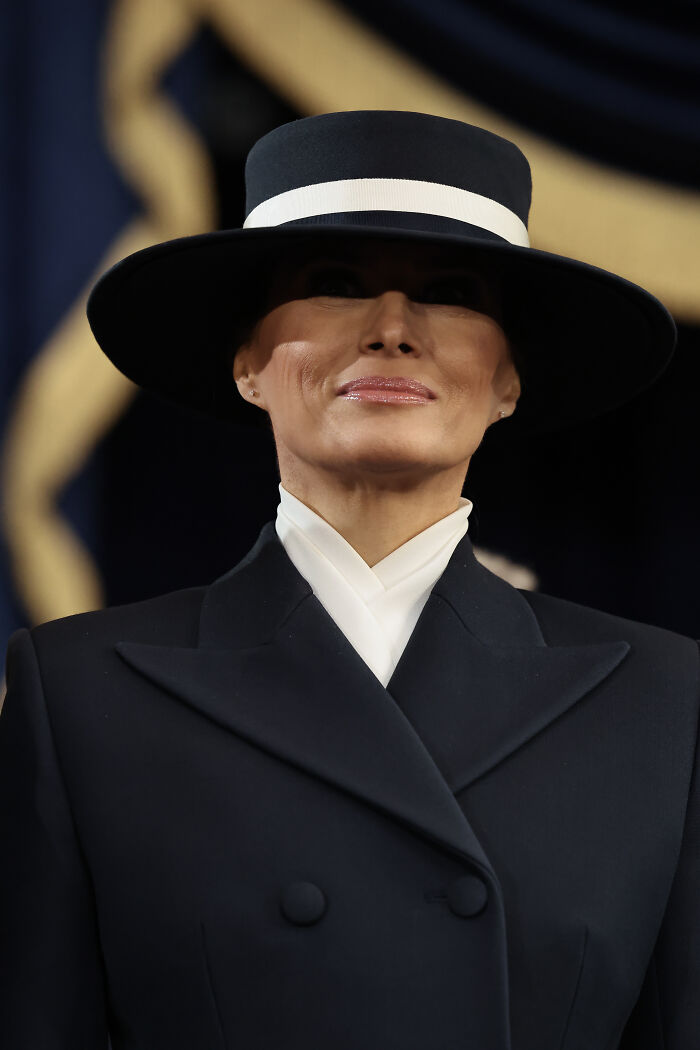 Woman in a black hat and coat, sparking body double rumors at an event.