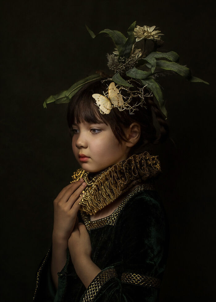 Creative photo of a child in period costume with intricate headpiece, set against a dark background.