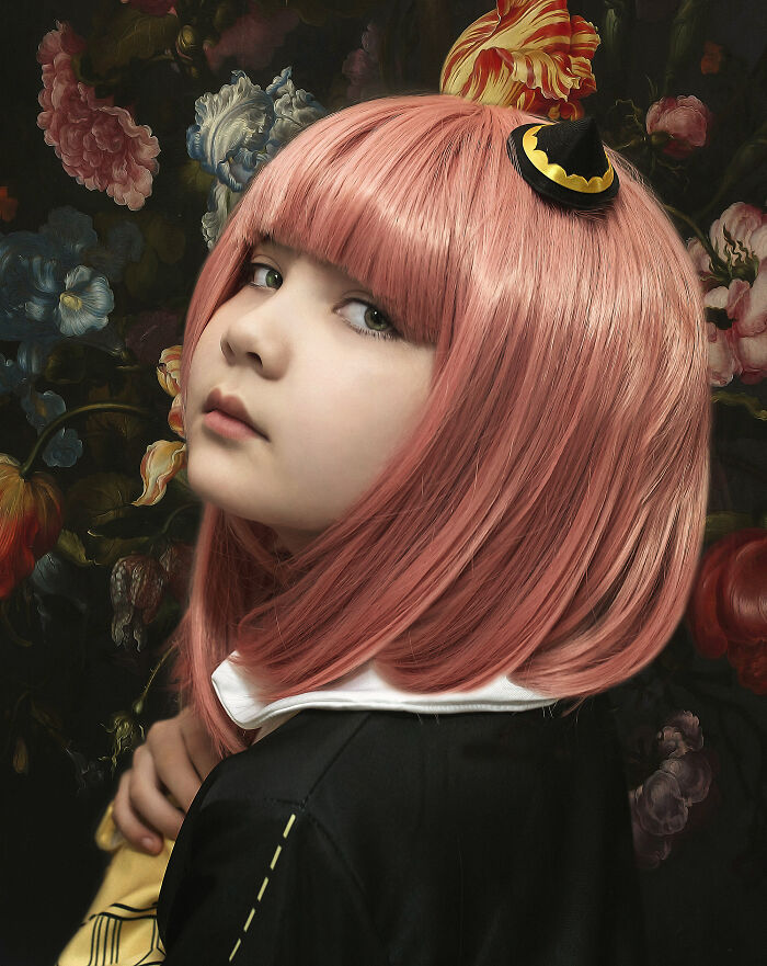 Child with pink hair in a creative photo shoot, wearing a small black hat with a floral background.