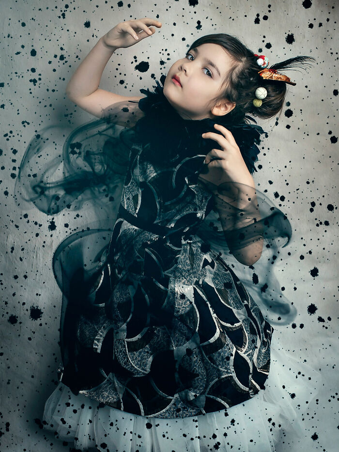 Creative photo of a young girl in a patterned dress against a speckled background, showcasing imaginative photography.