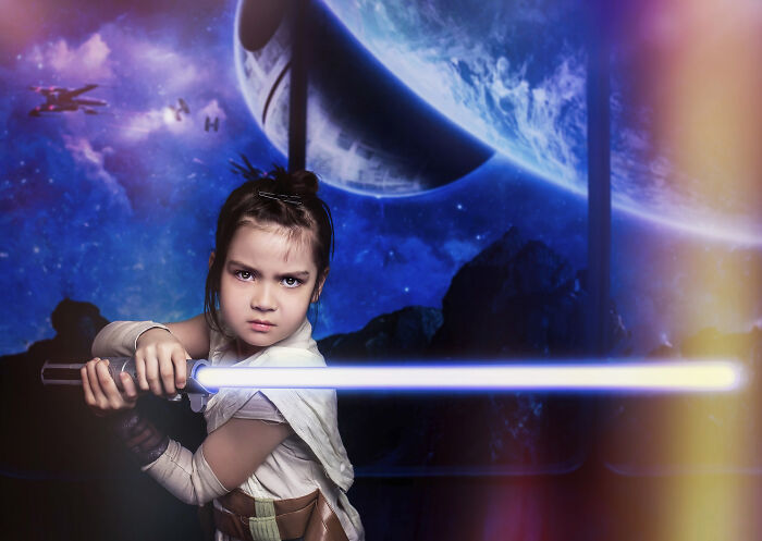 Creative photo of a child dressed as a space warrior with a glowing sword in a cosmic setting.
