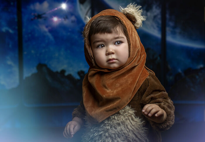 Child in a creative costume resembling a fantasy character, set against a cosmic background.