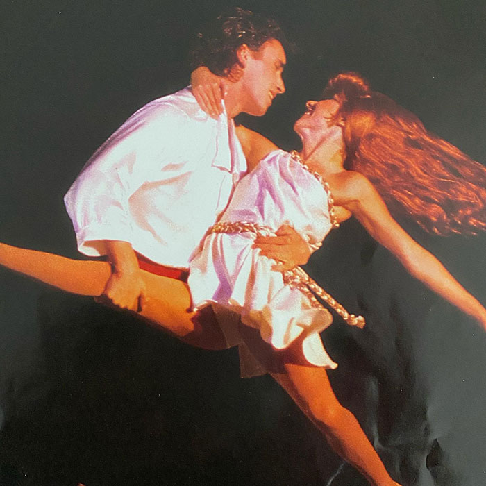 Disney On Ice performers dancing gracefully on stage under bright lights.
