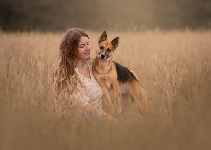 Woman sitting in a field with a happy dog, from International Pet Photographer Awards 2024.