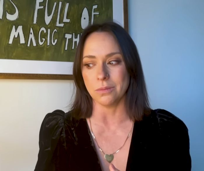 Woman sitting in front of a framed artwork, looking thoughtful.