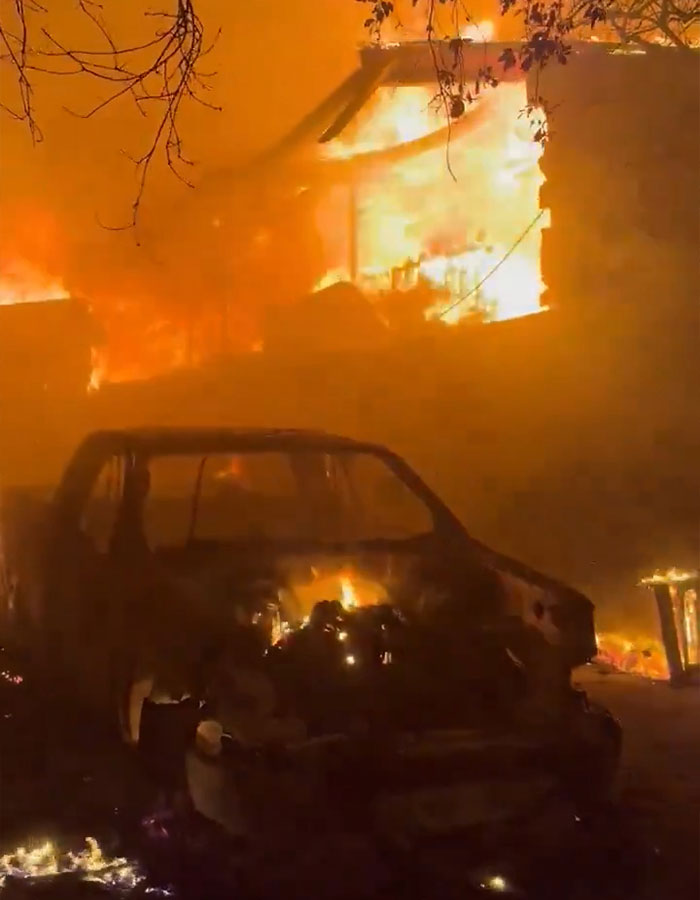 LA firefighters battle intense blaze, engulfing a building and vehicle in flames.