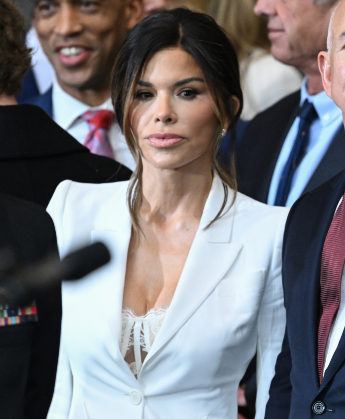 Woman in a white suit at a presidential inauguration event, surrounded by people.