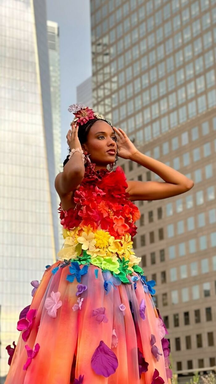 Fashion prodigy showcasing a colorful, floral dress against a cityscape background.