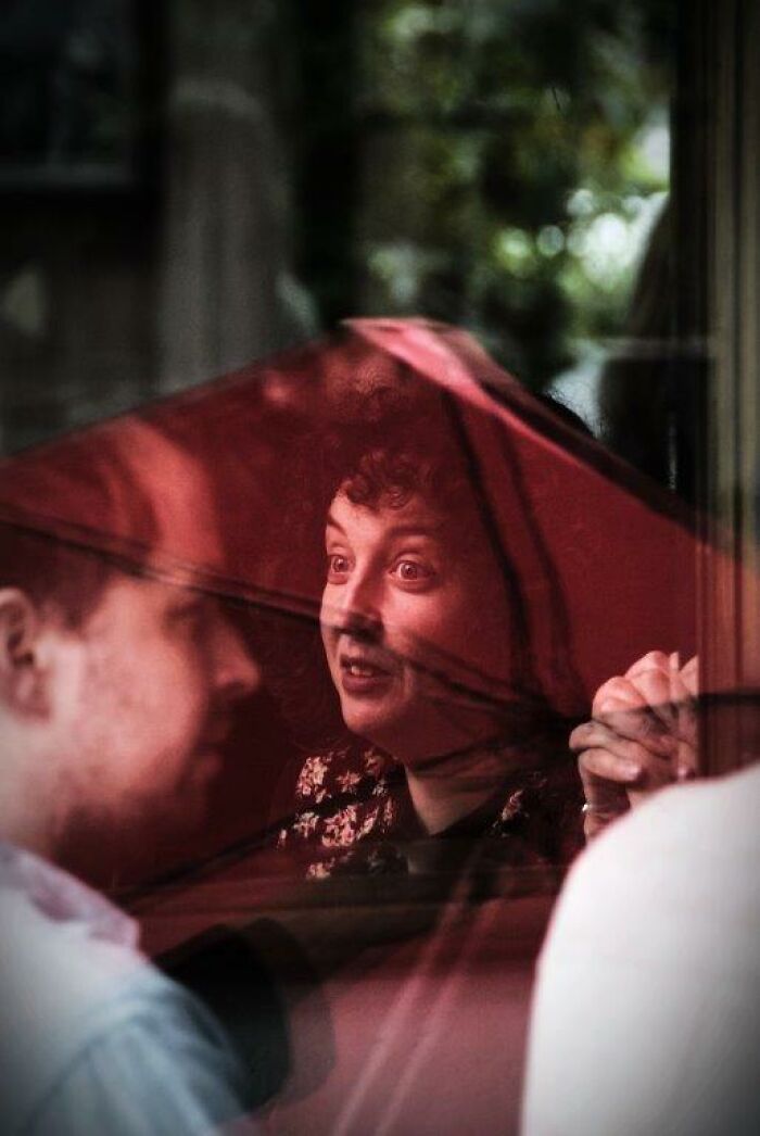 Everyday moments captured through a red umbrella lens, showing a woman engaged in conversation.