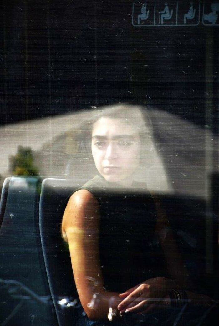 Woman seen through a reflective window, capturing everyday moments with reflective lighting and contemplative mood.