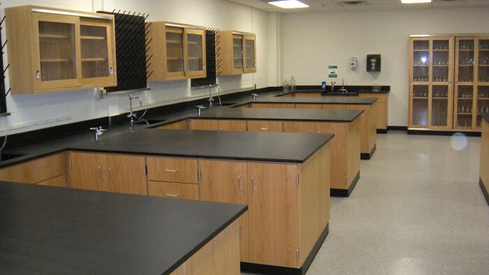 Old-school science lab with wooden cabinets and black countertops, evoking memories of past classroom settings.