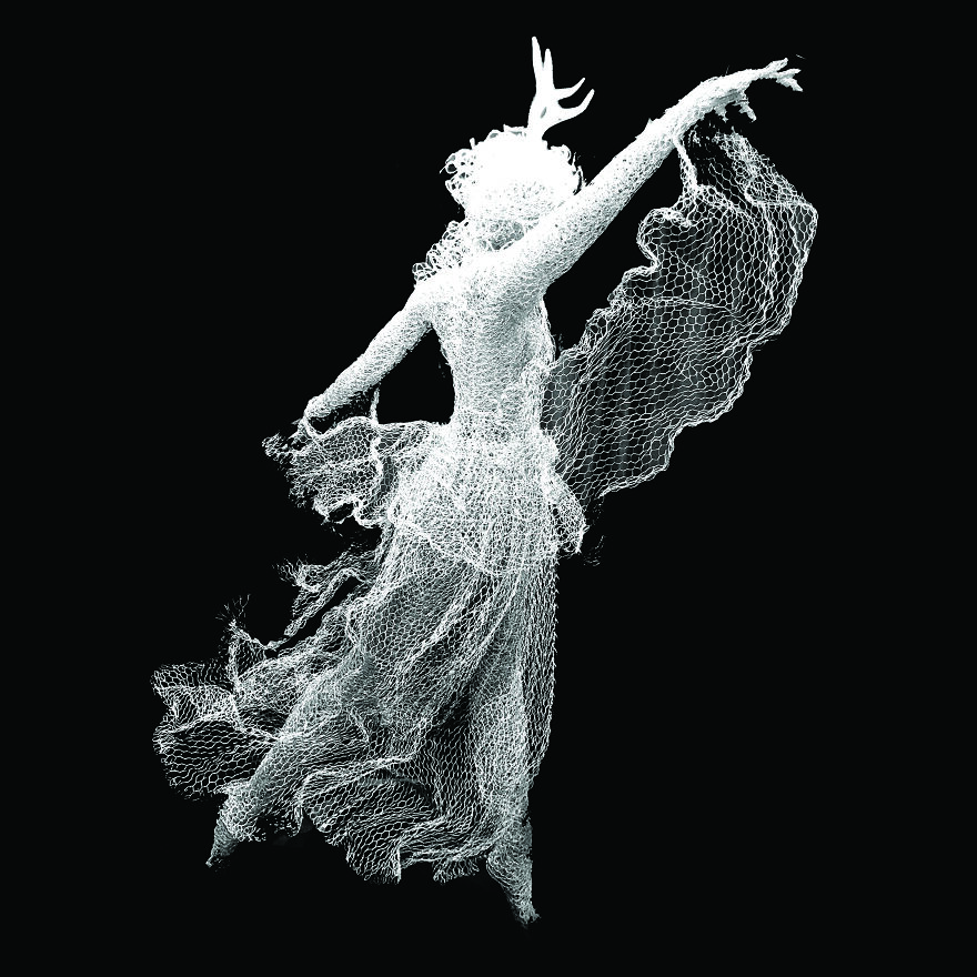 Chicken wire sculpture of a graceful dancer with an extended arm, capturing movement and fluidity in white wire mesh.
