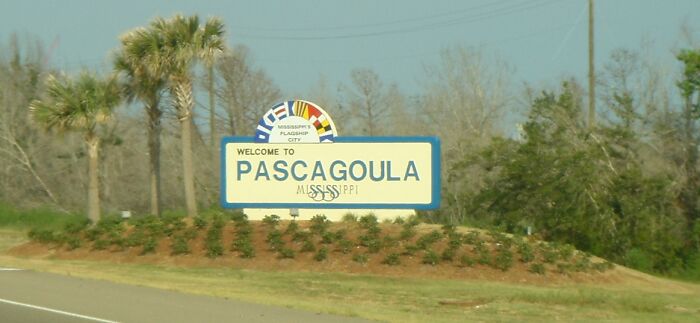 "Welcome to Pascagoula sign, associated with weird unsolved mysteries, set against trees and a clear sky."