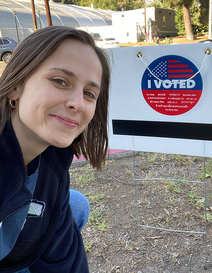 Pauline Chalamet poses with an "I Voted" sign outdoors, smiling and wearing a blue jacket. Pauline Chalamet poses with an "I Voted" sign outdoors, smiling and wearing a blue jacket.