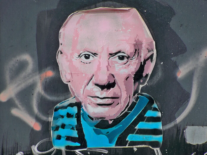 Graffiti art of an older man's face wearing a striped shirt on a textured wall; connected to overlooked historical events.