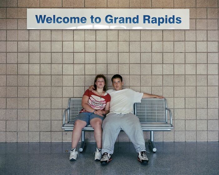 Two people sitting on a bench at a bus stop in Grand Rapids, part of a photographer’s series documenting America by bus.