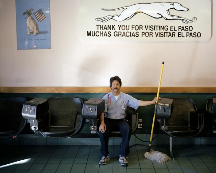 Man sitting at a bus stop bench with a mop, under a sign thanking visitors to El Paso, documenting life at America’s bus stops.