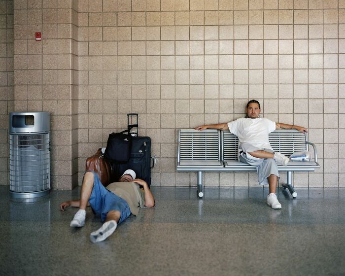 Two men waiting with luggage inside a bus station capturing life at America’s bus stops by photographer.