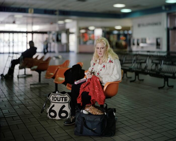 Woman sitting at an empty bus stop on Route 66, captured in a photograph documenting life at America's bus stops.