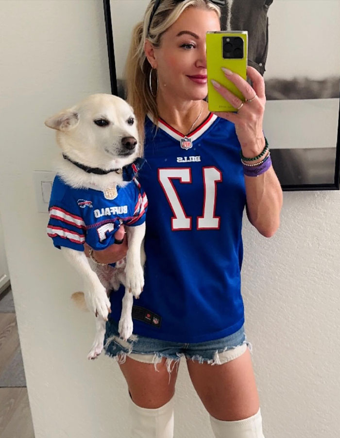 Woman in Buffalo Bills jersey holding dog in matching attire, capturing a selfie. Woman in Buffalo Bills jersey holding dog in matching attire, capturing a selfie.
