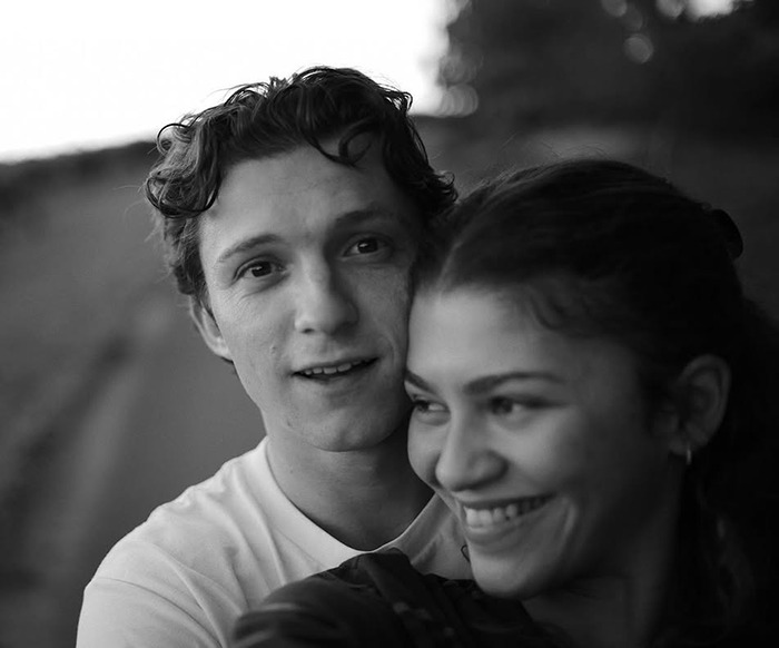 Zendaya and Tom Holland smiling together in an outdoor setting, highlighting a romantic and intimate moment.