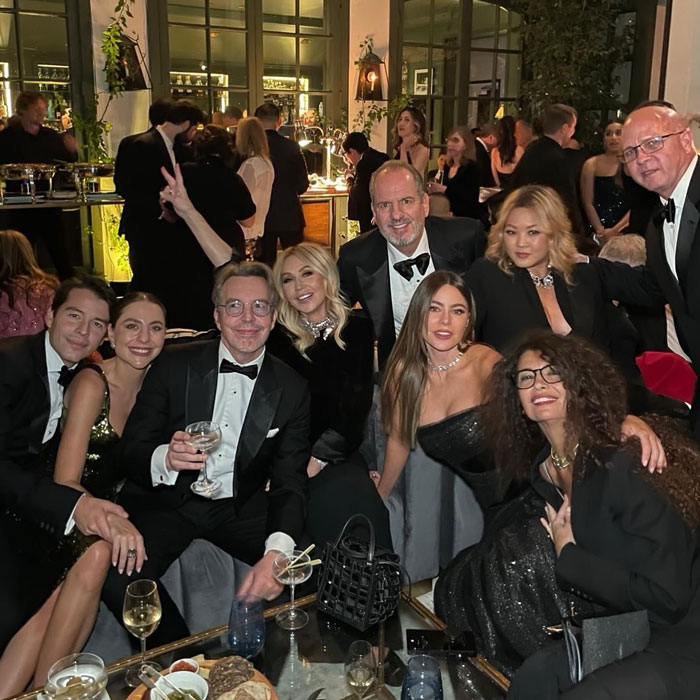 Group of people at an event in formal attire, including Sofia Vergara, sitting and posing in a lively setting. Group of people at an event in formal attire, including Sofia Vergara, sitting and posing in a lively setting.