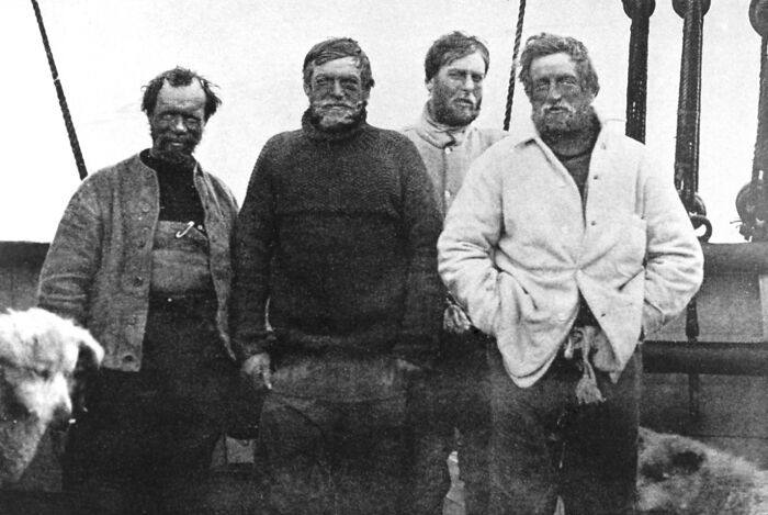 Four explorers pose on a ship deck, epitomizing overlooked historical events in early 20th-century polar expeditions.