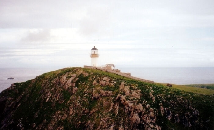 Lighthouse on a remote cliff with mist, symbolizing weird unsolved mysteries.