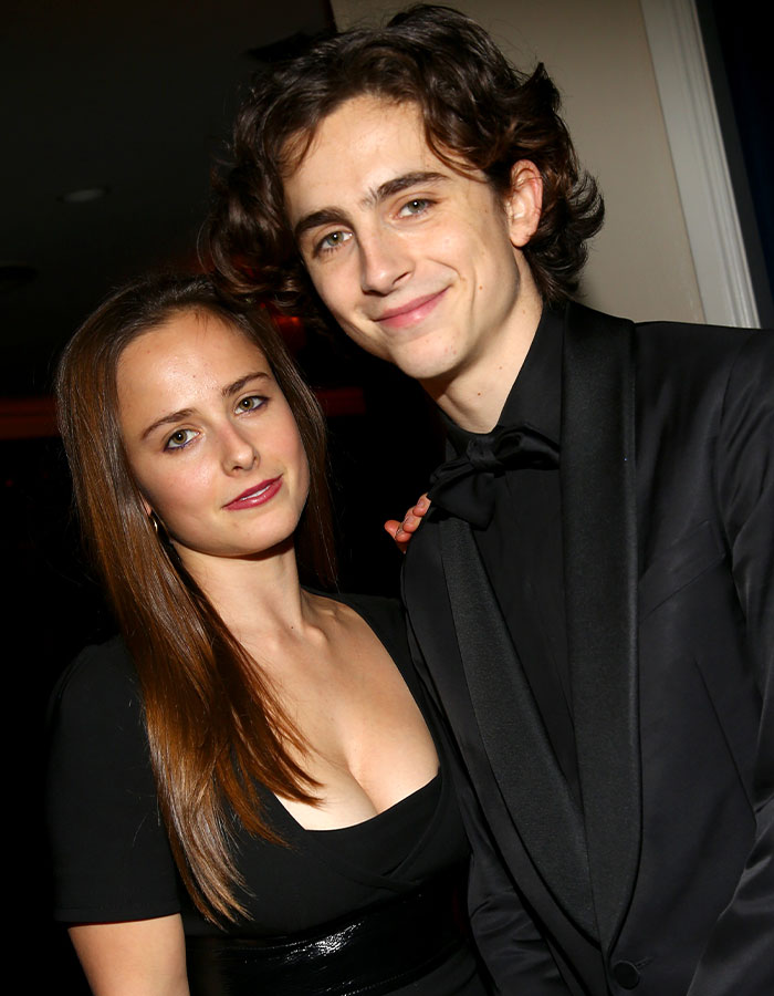 Brother and sister in formal attire at an event, both smiling, with the sister looking confidently at the camera. Brother and sister in formal attire at an event, both smiling, with the sister looking confidently at the camera.