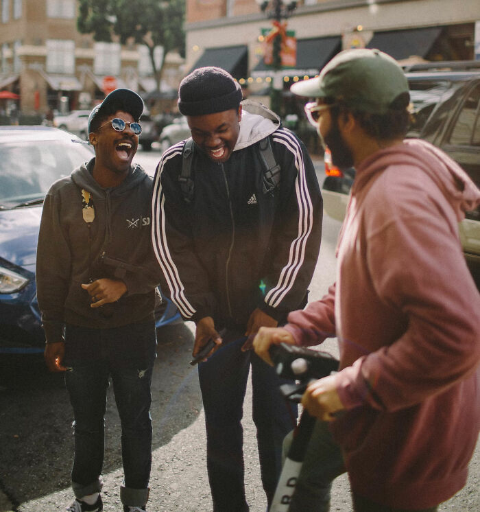 Group of friends laughing together in a lively street, showcasing youthful behavior and maturity dynamics.