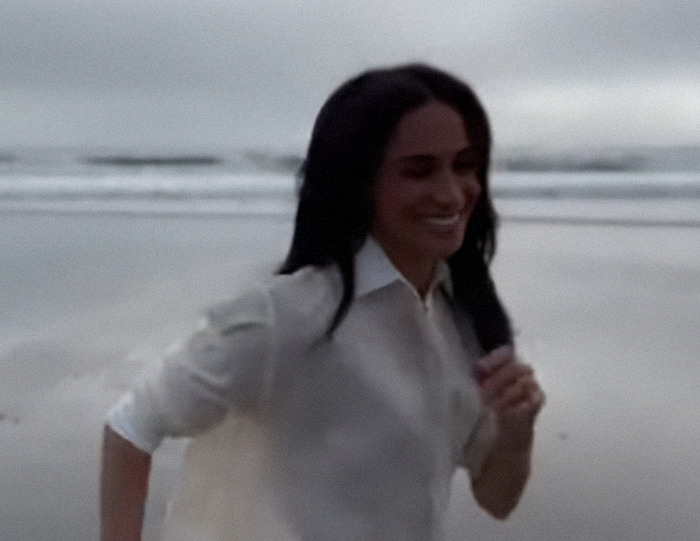 Meghan Markle in white shirt smiling and running on a beach, promoting Instagram video comeback. Meghan Markle in white shirt smiling and running on a beach, promoting Instagram video comeback.