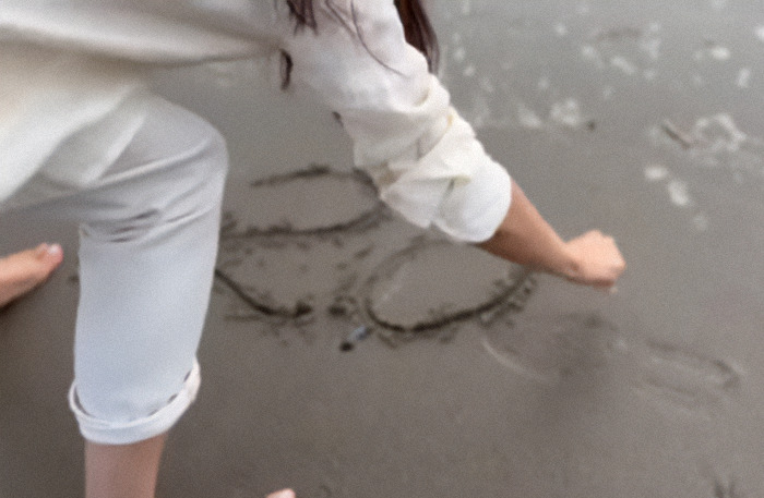 Meghan Markle writing on sand at the beach, wearing a white outfit; part of Instagram comeback video. Meghan Markle writing on sand at the beach, wearing a white outfit; part of Instagram comeback video.