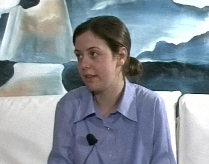 Sister Clare Crockett speaking, wearing a blue shirt, with a painting in the background. Sister Clare Crockett speaking, wearing a blue shirt, with a painting in the background.