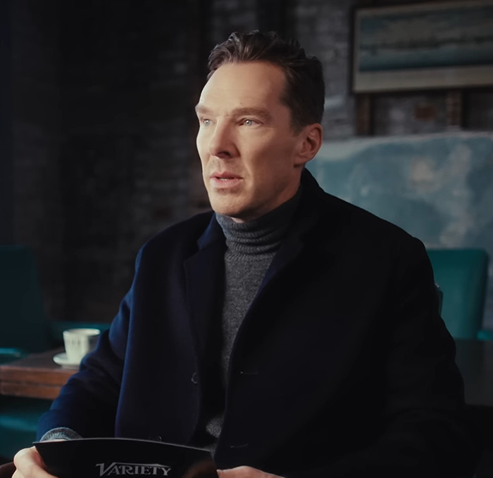Benedict Cumberbatch seated indoors wearing a dark coat and gray turtleneck. Benedict Cumberbatch seated indoors wearing a dark coat and gray turtleneck.