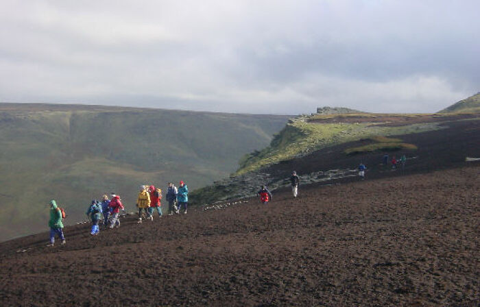 Group of hikers exploring a strange, barren landscape under cloudy skies, evoking weird unsolved mysteries.