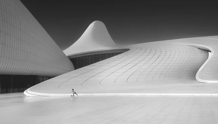 A person running beside a futuristic building, showcasing a winning photo from The Artist Gallery Awards.