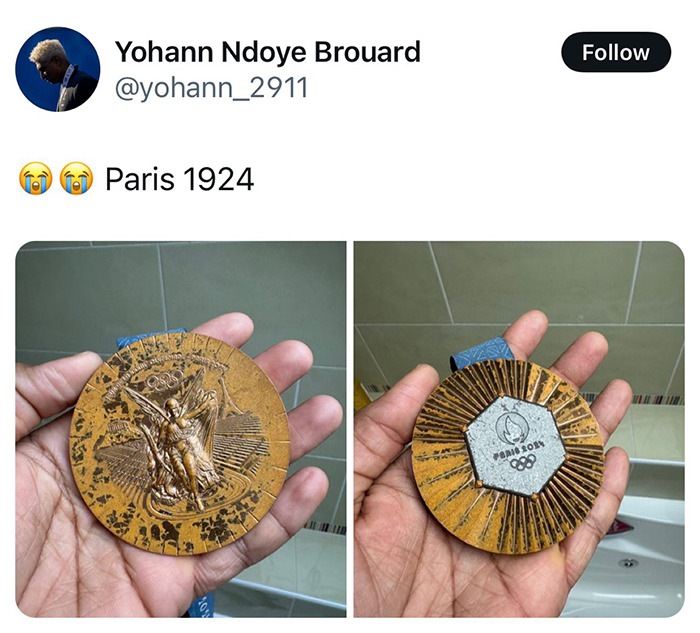 Athlete holding a Paris Olympic medal in hand, featuring intricate designs on the front and back.