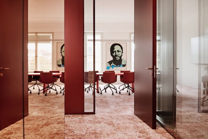 Modern interior design with red chairs and artwork in a conference room, showcasing award-winning design excellence.