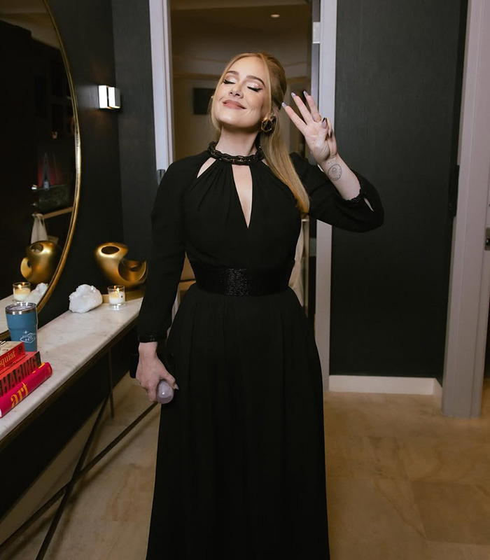 Adele in a black dress with a peace sign, next to a mirror. Adele in a black dress with a peace sign, next to a mirror.