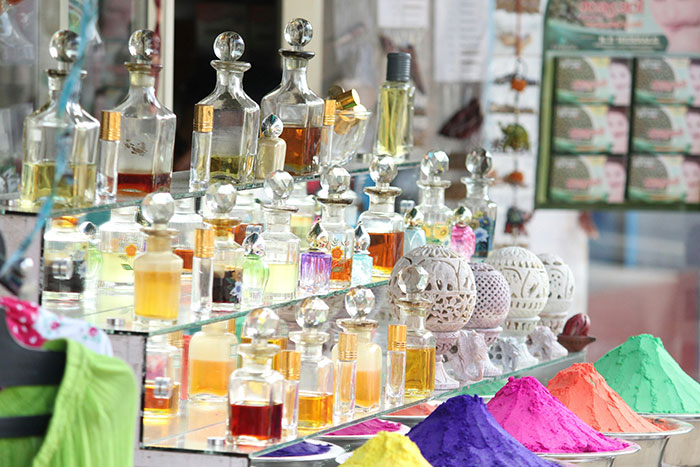 Perfume bottles on display with colorful powders in a market setting.